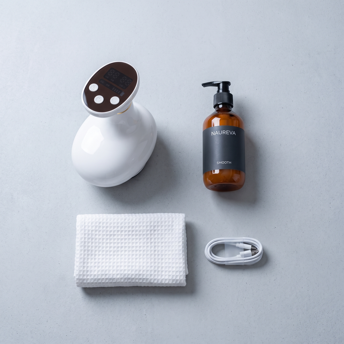 The Naureva Glide with a bottle of Smooth oil, a towel and a charging cable